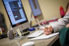A student doing schoolwork with a computer and notebook.